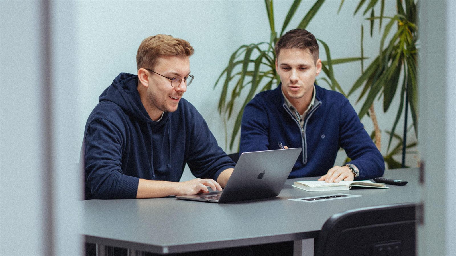Zwei Mitarbeiter von PlusPotenzial besprechen einen Entwurf am Laptop